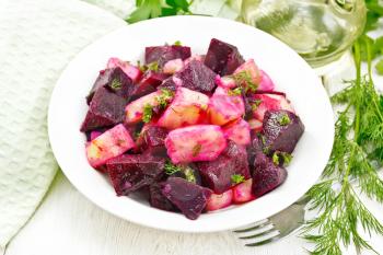 Salad of beets and potatoes, seasoned with vegetable oil and vinegar in a plate, napkin, fork, parsley and dill on a wooden board background