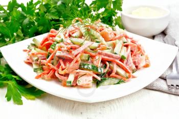 Salad from smoked sausage, spicy carrot, tomato, cucumber and spices, dressed with mayonnaise, towel, fork and parsley on a wooden board background