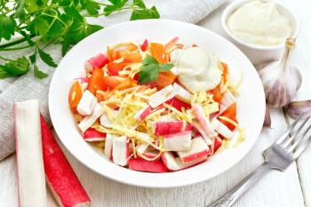 Salad of crab sticks, cheese, garlic and tomatoes with mayonnaise, napkin, parsley on a wooden board background