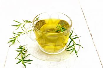Rosemary herbal tea in a cup with a saucer on a wooden board background
