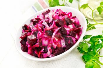 Vinaigrette salad with pickled or sauerkraut, potatoes, beetroot and onions, seasoned with vegetable oil in a bowl, napkin, parsley on a wooden board background