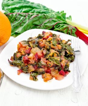 Warm chard salad with orange and onion in a plate, toasted bread, fork on a light wooden board background