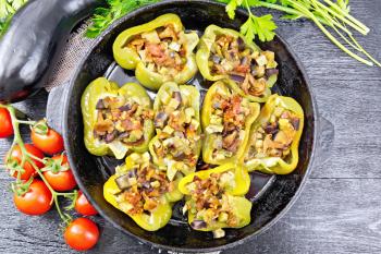 Pepper sweet stuffed with mushrooms, tomatoes, zucchini, eggplant and onions, seasoned with wine, garlic, thyme and spices in a frying pan on a napkin of burlap against wooden board on top