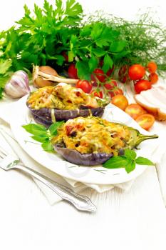 Stuffed eggplant with smoked brisket, tomatoes, onions, carrots with garlic, cheese and herbs in an oval plate on a napkin on background of light wooden board