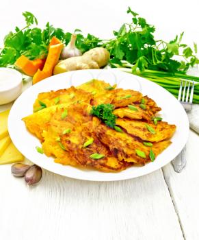 Fritters of pumpkin and cheese with ginger in a white plate, sour cream in a bowl, napkin, parsley and fork on background of light wooden board