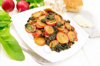 Radish stewed with spinach and spices in a plate, cheese and bread, a kitchen towel against wooden board background