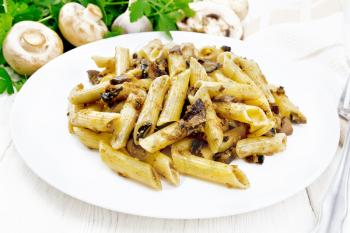 Penne pasta with wild mushrooms in a plate, towel, parsley and fork on a wooden board background