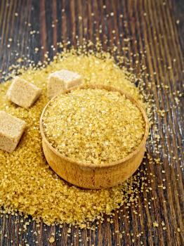Granulated brown sugar in a bowl and on a table, cubes on wooden board background