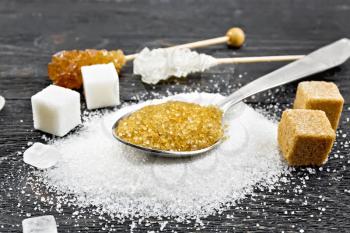 Brown granulated sugar in a metal spoon, white granulated sugar on a table, crystalline and cubes on wooden board background