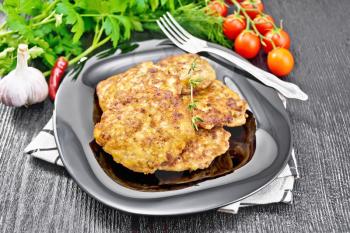 Fritters of minced meat in a plate with a fork on towel, garlic, parsley and hot pepper on wooden board background