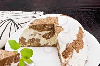 Dessert of cottage cheese and cocoa with gelatin and sugar in a white plate, towel and a spoon on wooden board background