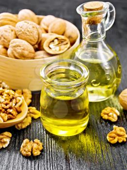 Walnut oil in a jar and decanter, nuts in a box, spoon and on table on wooden board background