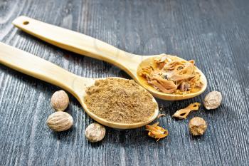 Ground nutmeg and dried nutmeg arillus in two spoons, whole nuts on a wooden board background
