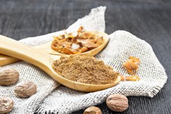 Ground nutmeg and dried nutmeg arillus in two spoons, whole nuts on burlap on a dark wooden board background
