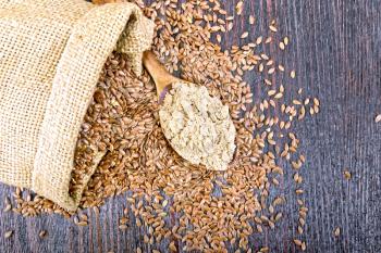 Flax flour in a spoon, seeds in a bag and on a table on the background of a wooden board from above