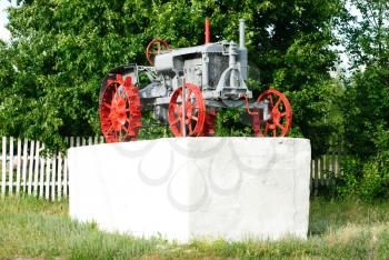 An old tractor on a  white pedestal. Ukraine. Poltava region.