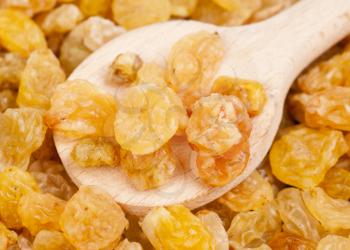 Golden raisins close- up and wooden spoon, food background