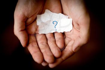 Royalty Free Photo of Hands Holding a Scrap of Paper With a Question Mark