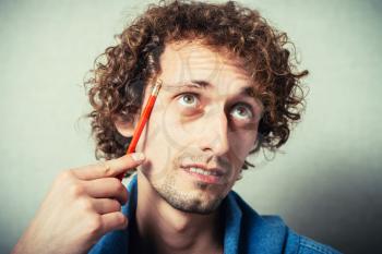 Portrait of a young businessman holding a pencil and thinking.