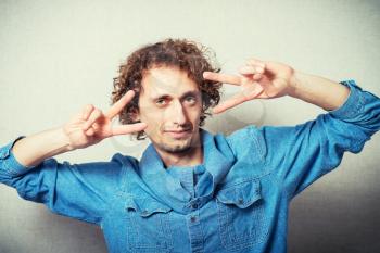 curly-haired man showing two fingers