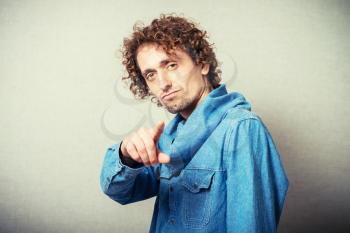 curly-haired man points a finger