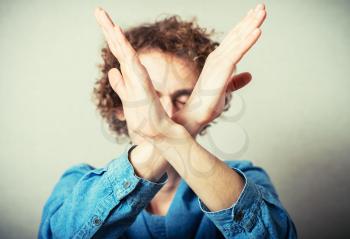 Curly young man gesture stop. On a gray background