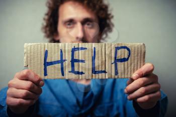 Curly man with a kraft cardboard with text donate help. On a gray background.