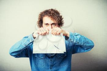 Curly man tearing white sheet of paper, contract, agreement or statement. On a gray background.