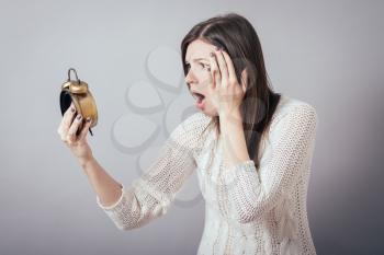 frightened girl holding a retro alarm clock