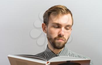 Portrait of young man reading isolated over grey background