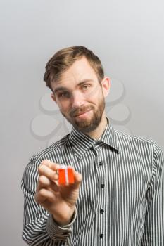 man holding a small red gift in his right hand, looking down.