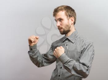 Closeup side view profile portrait of angry upset young man, worker, employee, business man fists in air, open mouth yelling, isolated. Negative  emotion facial expression emotion
