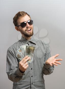 a young man  isolated over a gray background holding banknotes