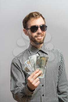 a young man  isolated over a gray background holding banknotes
