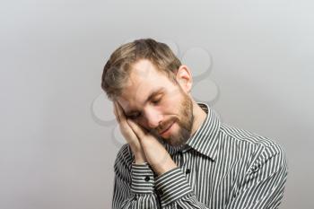 Handsome young businessman with hands behind head sleeping on wooden wall