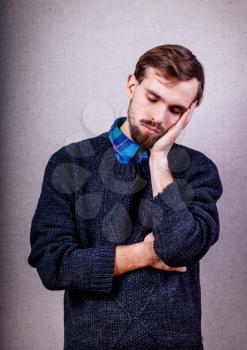 young man with beard in blue sweater dozing