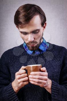 Young male with beard, blowing  in cup of tea
