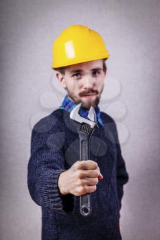 Young builder with adjustable wrench in hand looking at camera