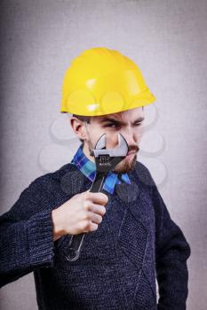 Young builder looking through a wrench