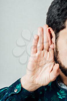 Young serious man   holding an ear to listen better, what you're saying. Photo Shoot.