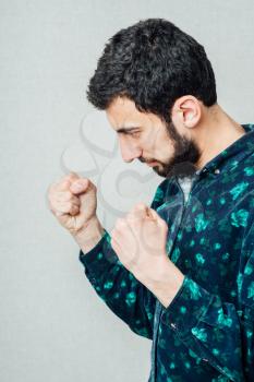 Aggressive adult man strikes blow with the clenched fist to camera, isolated on white background