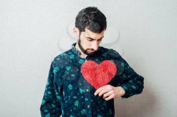 A young man holding a red heart in his hands