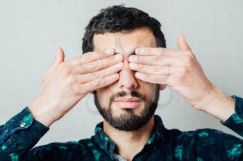 Portrait of a young man covering his eyes with hands