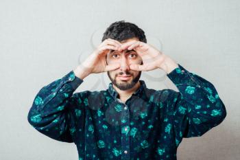  man  looking through hands, making binoculars