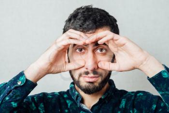  man  looking through hands, making binoculars