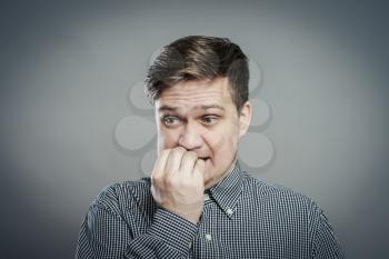 portrait of thinking man with fingers in mouth, biting fingernail. Negative emotion, facial expression