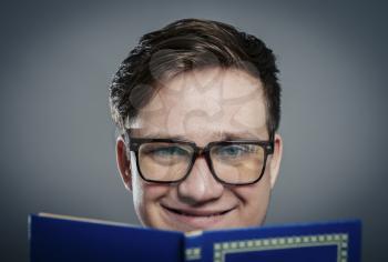 Portrait of young man in glasses reading isolated over grey background