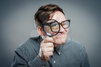 Funny image of a adultman with a magnifying glass, one eye is enlarged.