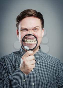 Man examining his teeth with magnifier
