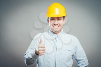 Portrait of smiling handyman with tools and paper showing thumbs up sign   isolated on  white background